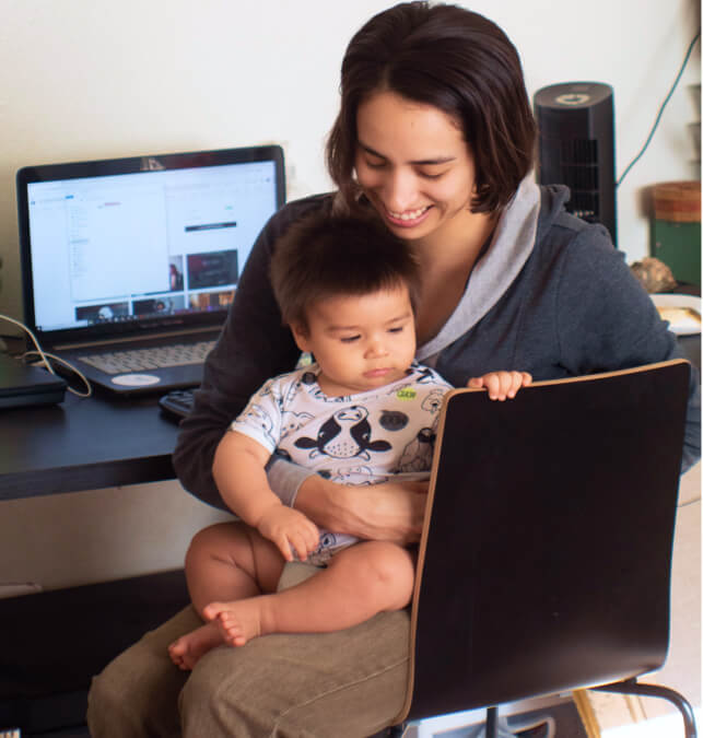 Woman holding child on computer.